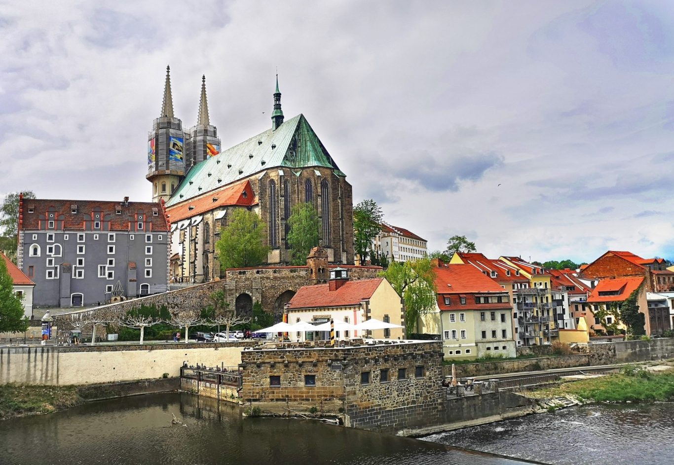 Detektei Görlitz Historisches Gebäude mit Türmen, umgeben von einer malerischen Stadtansicht am Fluss.