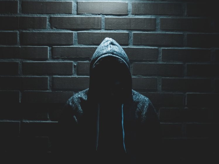 Fiktive Fallbeispiele aus Halle und Freiberg Silhouette einer Person in Kapuzenpullover vor einer dunklen Backsteinwand.