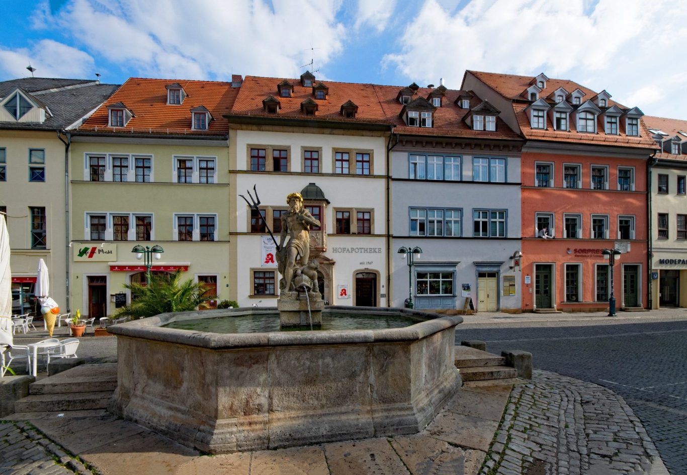 Privatdetektiv Weimar Brunnen in der Stadtmitte mit bunten Häusern im Hintergrund und blauen Himmel.