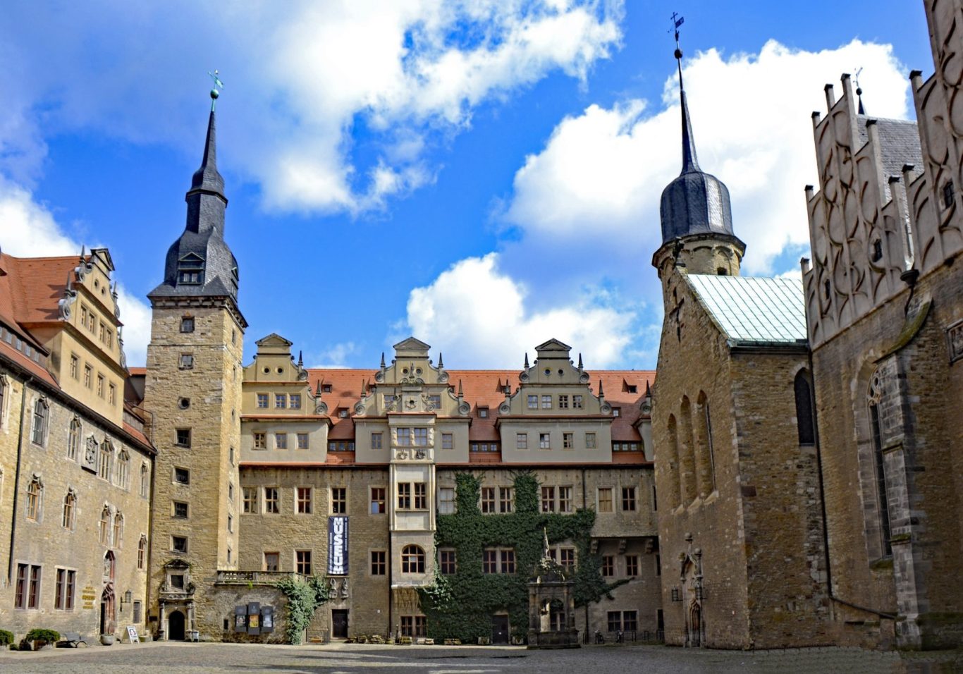 Privatdetektiv Merseburg Blick auf einen historischen Schlossinnenhof mit Türmen und Wolken am Himmel.